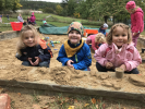 Děti stavějí bábovky z písku 